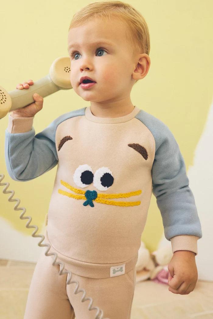 Conjunto de chándal bebé gato beige y azul con huellas en rodillas